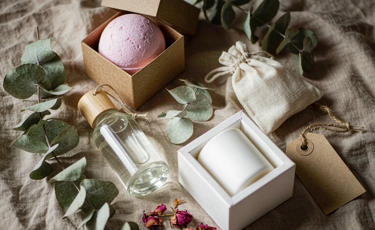 A private label OEM bath and body gift set with a bath bomb, shower gel and candle arranged on linen with eucalyptus